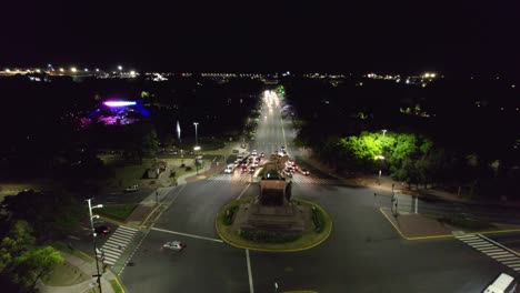 Dolly-in-aerial-view-of-the-street-at-night-with-low-traffic-and-the-Urquiza-Monument-and-Planetarium-unlit,-Buenos-Aires,-Argentina