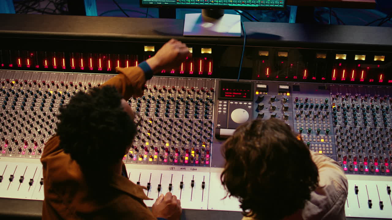 Music production team examining volume levels on audio software