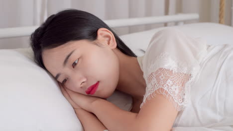 real shot of beautiful girl getting up in white pajamas waking up in her bed sitting near the big window fully rested and open the curtains stretching in the morning to get fresh air and sunshine