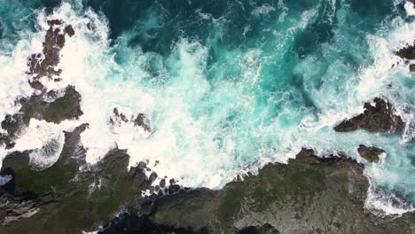 Fotografía-Aérea-Estática-De-Fuertes-Olas-Marinas-Del-Océano-Índico-Golpeando-Rocas-Y-Arrecifes-De-Coral-En-La-Playa-En-Condiciones-Soleadas---Pengilon-Hill,-Indonesia,-Asia