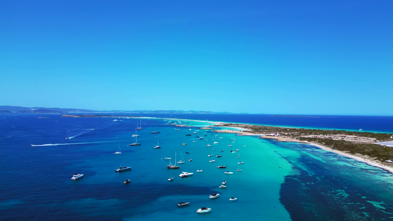Barche ancorate nelle splendide acque cristalline turchesi di Formentera, una spiaggia di sabbia bianca con Posidonia oceanica. Fantastica panoramica aerea dolly left overview drone
