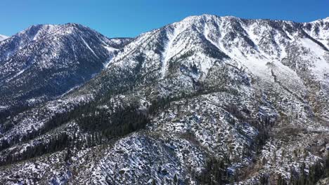 Drone-footage-flying-towards-large-mountain-covered-with-light-snow