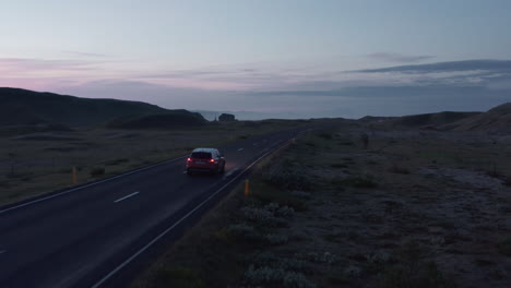 Luftbildauto,-Das-Bei-Sonnenuntergang-Auf-Einer-Leeren-Landstraße-Fährt.-Vogelperspektive-Auto-Fährt-Schnell-Auf-Der-Ringstraße,-Der-Wichtigsten-Autobahn-In-Island