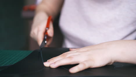 experienced worker cuts black leather fabric template