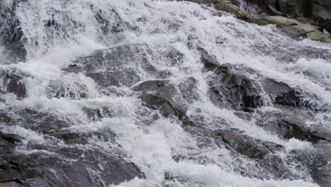 Goa-Rang-Reng-waterfall-captured-in-a-tilt-up-shot,-revealing-the-cascading-water-first,-then-transitioning-to-the-lush-jungle-canopy-above