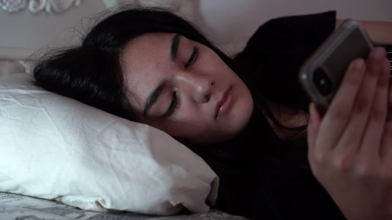 chica enviando mensajes de texto en su teléfono en el medio de la noche