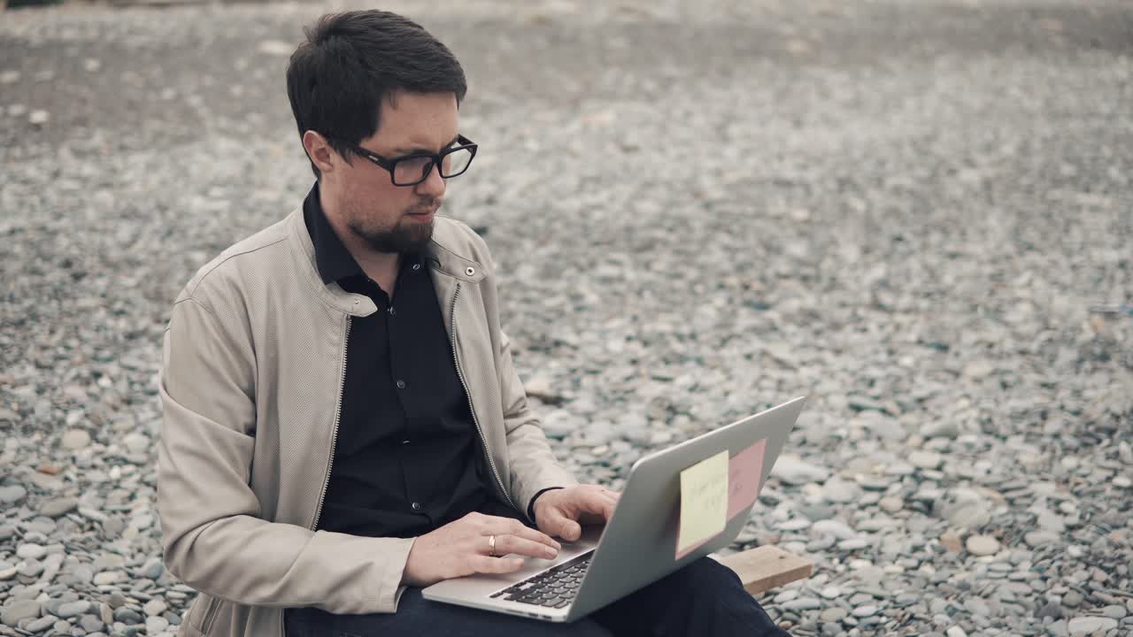 hombre trabajando en una computadora portátil en la playa