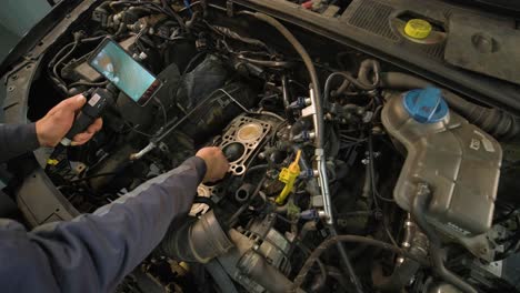 hands of car mechanic check the vehicle engine with technical endoscope with rotary camera and mobile phone. repair of engine head and valves.