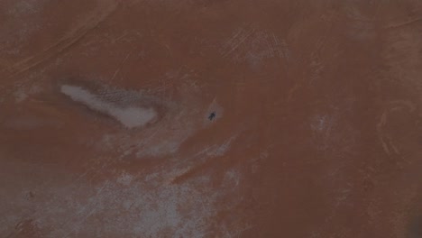 clip aéreo de suelo desértico seco y agrietado, con un hombre tendido en el suelo en traje de buceo para resaltar la sequía y la escasez de agua debido al cambio climático
