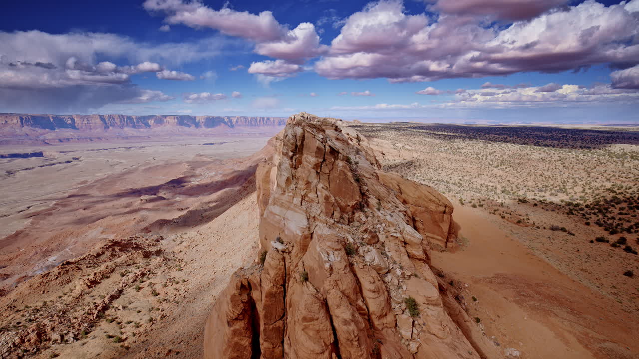 High-altitude drone shot sweeping over the mountain ridge, emphasizing the sudden vertical plunge near Antelope Pass Vista on the road to Page, Arizona.
