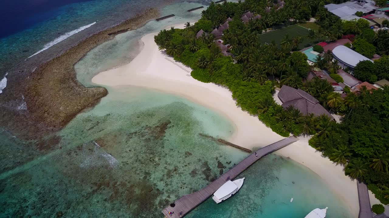 몰디브의 섬 - 게스트하우스, 나무 산책로, 청록색 바다로 둘러싸인 해안에 정박한 보트가 있는 하얀 모래 위의 울창한 섬 - 공중 촬영