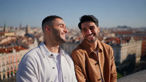 two happy men smiling and laughing on a city rooftop