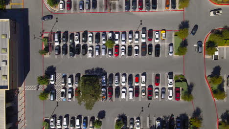 vista aérea de arriba hacia abajo del estacionamiento del centro comercial, personas y automóviles en el estacionamiento en busca de espacios, drone 4k