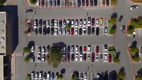 aerial top down view of shopping center parking lot, people and cars in carpark searching for spaces, drone 4k