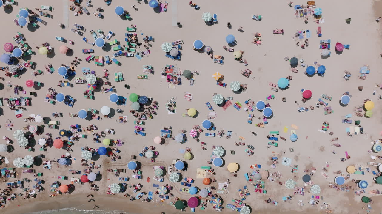 imágenes aéreas de arriba hacia abajo alejándose de los turistas en la playa con una variedad de colores en bari, italia