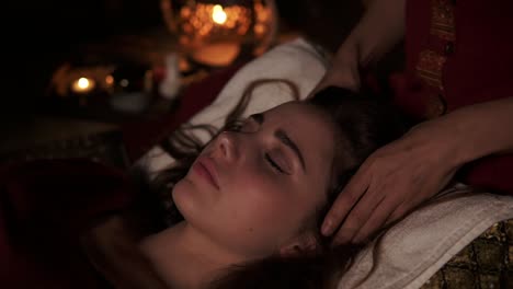 Close-Up-view-of-a-female-massage-therapist-doing-thai-massage-of-neck,-head-and-face-for-woman-on-couch-in-spa-room.-Slow-motion