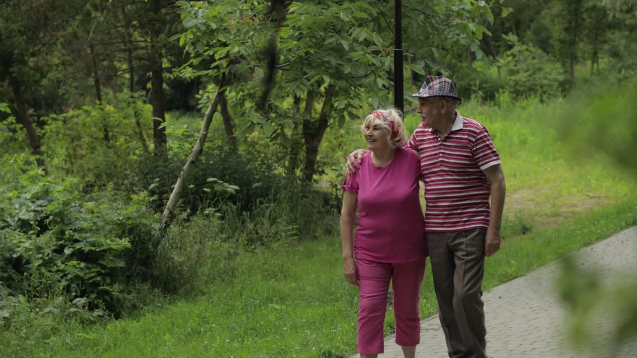 una pareja caucásica anciana caminando en el parque abrazándose. un hombre anciano camina con una mujer. marido, esposa