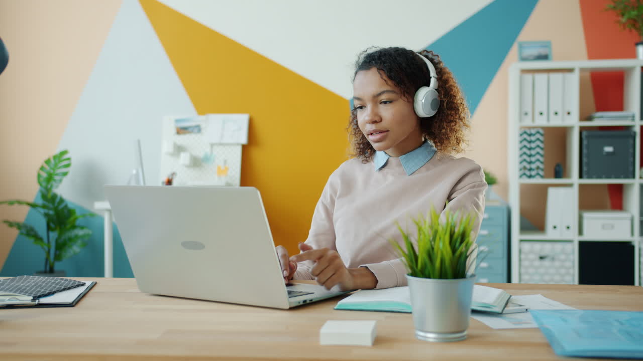 mujer trabajando en una computadora portátil con auriculares