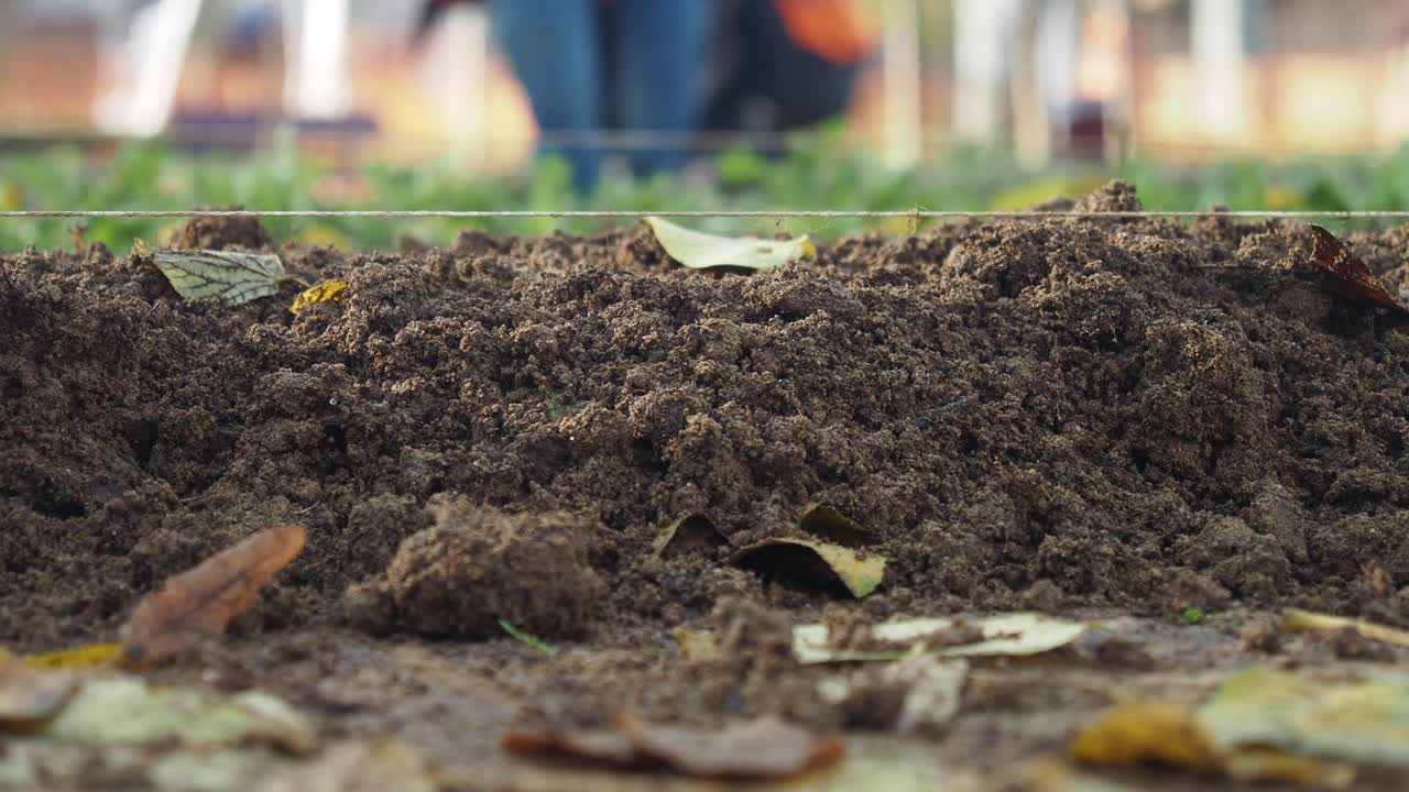 Primo piano di un cumulo di terra con persone sfocate che lavorano sullo sfondo