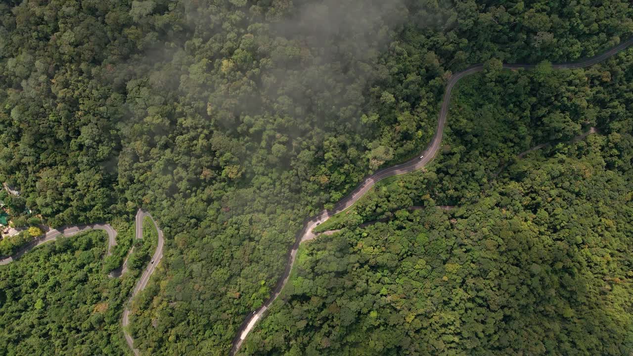 imágenes aéreas de la carretera rodeada de selva tropical y nubosidad