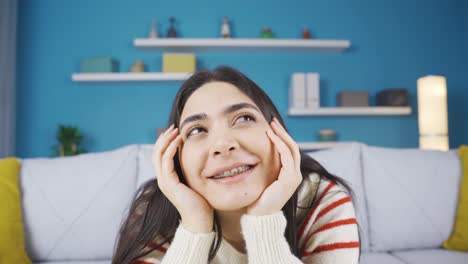 young woman sitting alone at home thinking about happy moments and smiling.