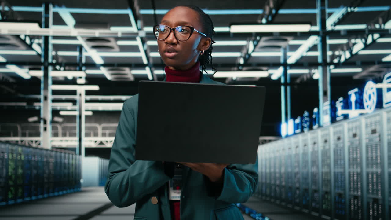 African American Woman Working on Laptop in Modern Data Center