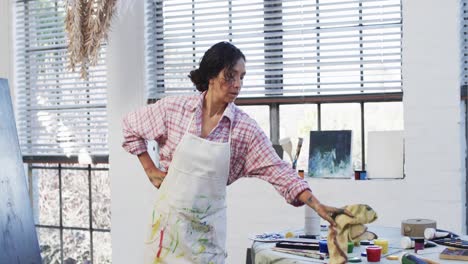 artista femenina biracial en delantal en un estudio de arte, cámara lenta