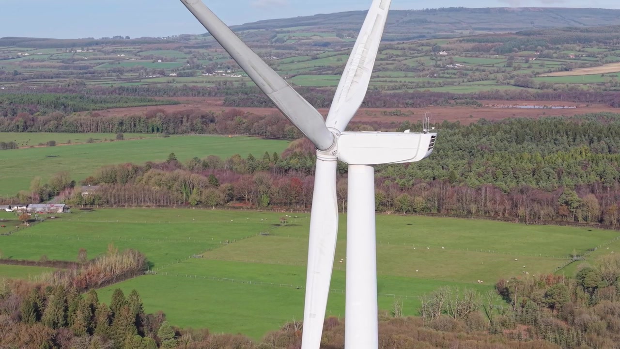 Primo piano di una turbina eolica con prato e foresta sullo sfondo nelle Midlands, Laoise, Irlanda. - ripresa aerea