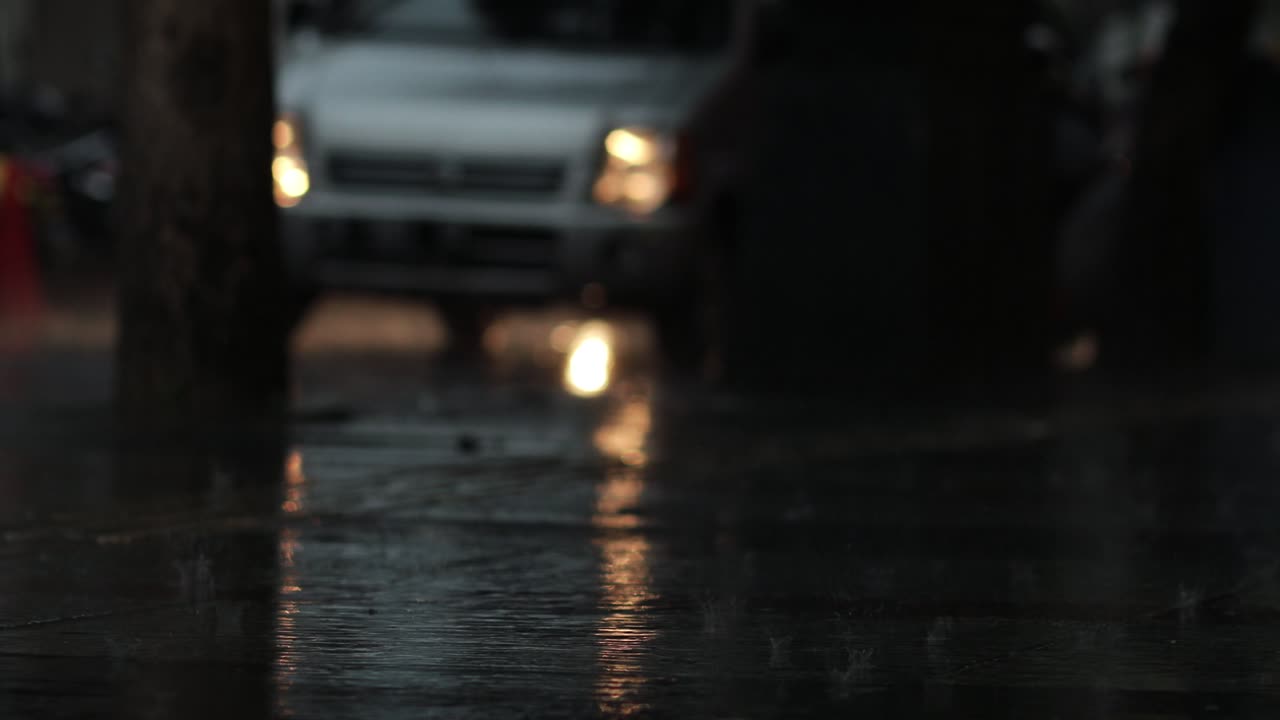 Vehicle headlights passing on the road during heavy rain condition in the evening
