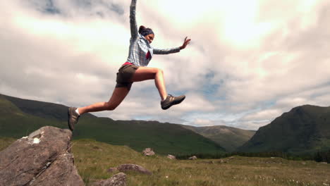 Athletic-woman-jumping-off-a-rock-in-the-countryside