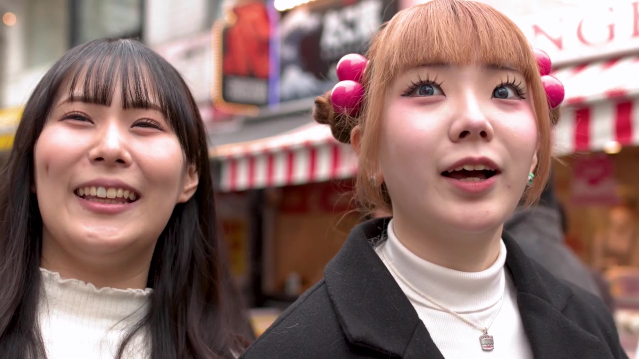 Due giovani donne asiatiche con abiti invernali eleganti parlano e sorridono in strada a Harajuku, Tokyo