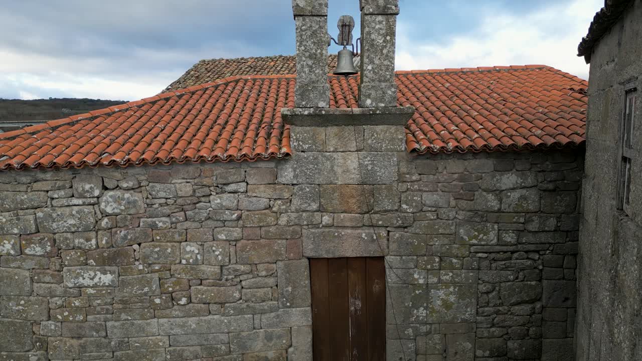 Chiesa di Santa Eufemia de Ambia con una vecchia porta di legno e un tradizionale muro a secco.