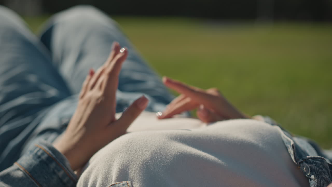Klidné prsty tančí v travnatém poli. Poklidná scéna s rukama vznášejícíma se a jemně zářícím slunečním svitem. Uvolněné ruce se ladně pohybují nad trávou uprostřed klidného slunečního svitu a venkovní pohody.