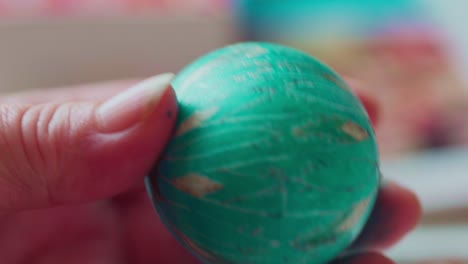 closeup of artist drawing ornate traditional designs on a green easter egg