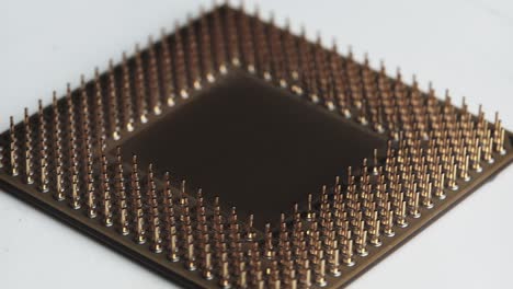 the computer processor cpu with gold plated contacts spins on white background