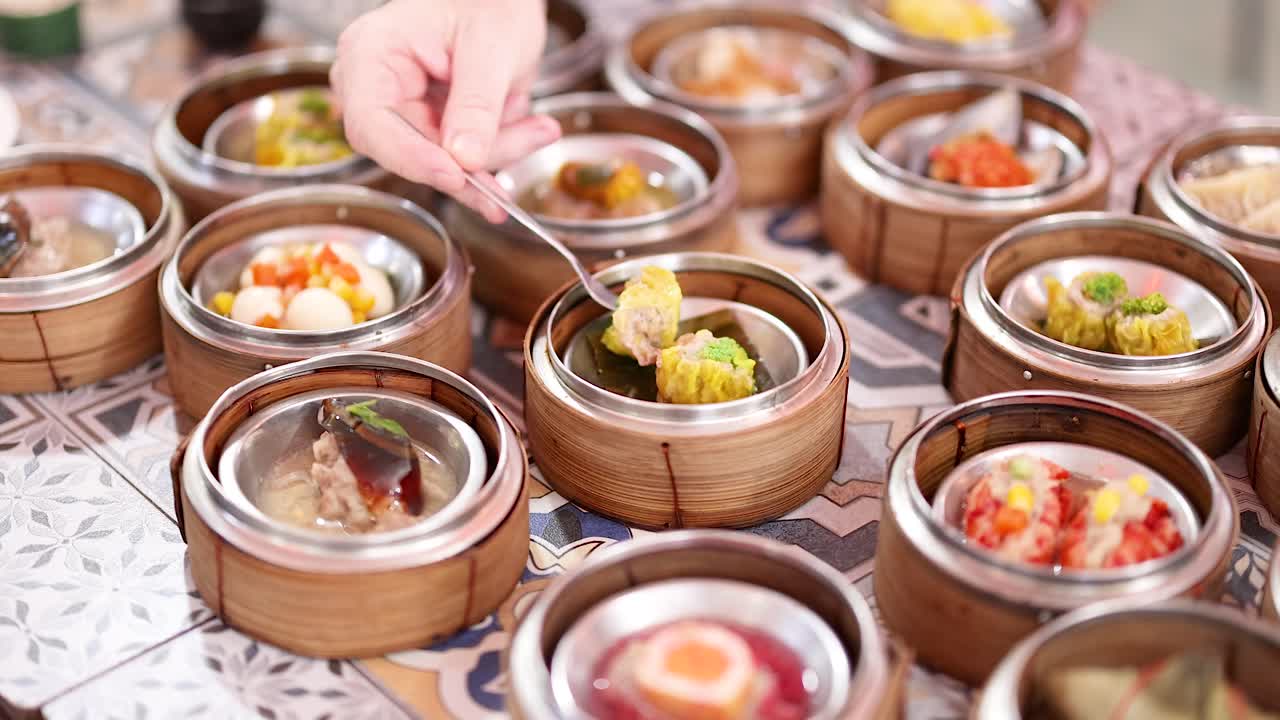 manos seleccionando dim sum de las cestas de bambú