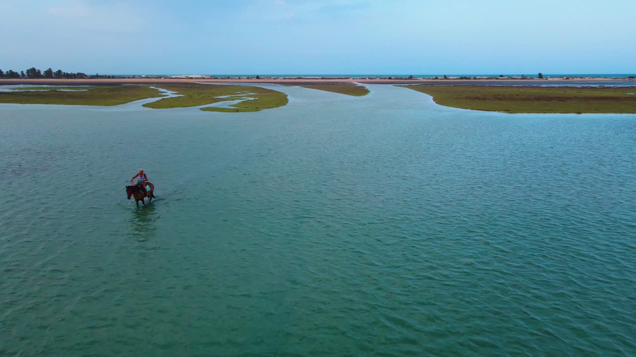 An aerial view of a women riding a horse through shallow water of the lagoon of Djerba at Tunisia