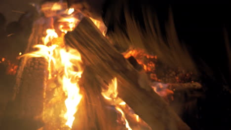 woman putting more wood in the fire at night