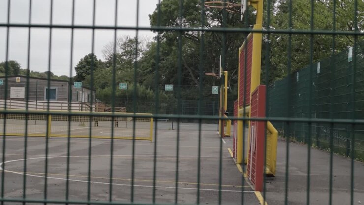 Vista di un parco giochi vuoto attraverso una recinzione, ripresa inclinata
