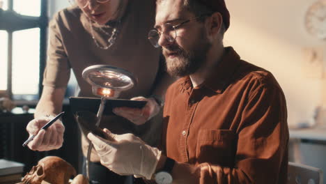 two researchers discussing artifact details in archaeology laboratory