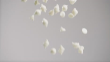 white chocolate chips raining down in slow motion 4k with gray backdrop