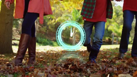 Neon-blue-digital-clock-ticking-against-low-section-of-family-holding-hands-walking-in-the-park