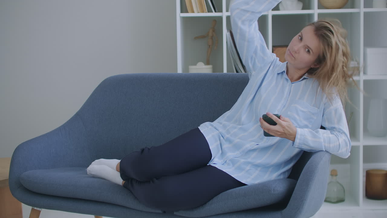 atractiva chica adolescente pelirroja sentada en el sofá en casa usando el teléfono y sonriendo. sentirse feliz. comunicación mujer buscando mensaje en el teléfono celular o smartphone.