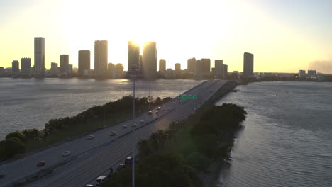 miami bridge with cars passing by with downtown miami in the background at dusk aerial shot