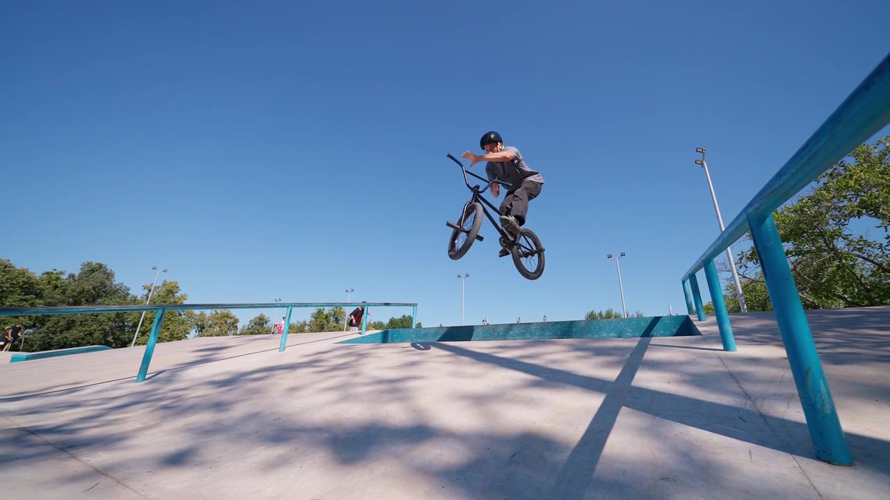 Młody mężczyzna na rowerze BMX wykonujący skok w skateparku
