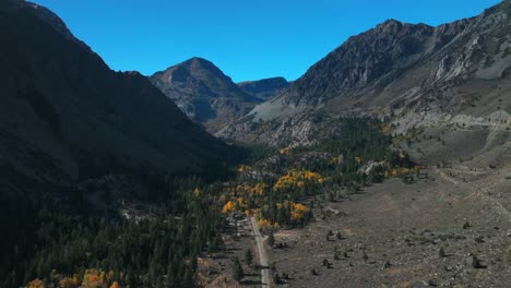 west portal entrance mountains lee vining tioga pass road yosemite national park california aerial drone ansel adams wilderness big oak flat fall autumn yellow orange aspen trees blue skies forward
