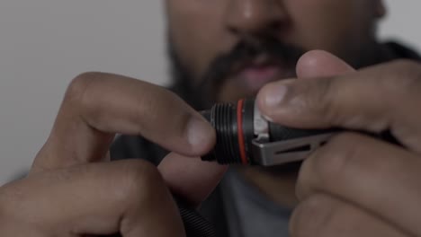 Close-Up-Of-Hands-Unscrewing-On-Battery-Cap-On-Portable-LED-Torch-To-Reveal-Battery