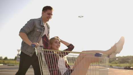 Slow-motion:-a-Free-and-cheerful-man-and-woman-ride-in-carts-in-a-supermarket-Parking-lot-shouting-and-raising-their-hands-in-the-air