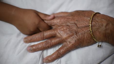 A-hand-of-a-little-girl-holds-an-Old-woman's-hand,-grand-daughter-holds-the-hand-of-her-grand-mother-or-granny,-affection,-love