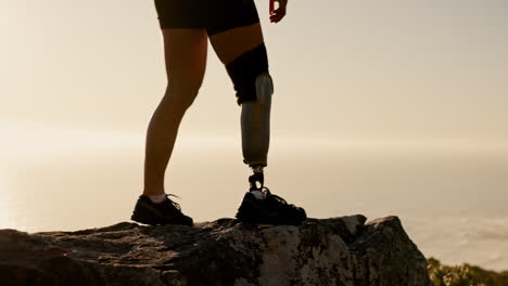 woman with prosthetic leg hiking on a cliff overlooking the ocean at sunrise/sunset.